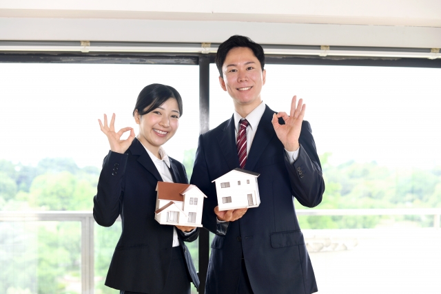OKマークを作って住宅模型を持つ男女