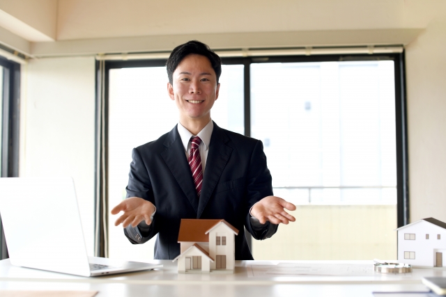 住宅模型の前で提案するスーツ姿の男性