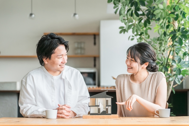 住宅模型を指さし笑顔の夫婦