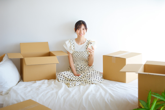 携帯を持ってあぐらのワンピースの女性
